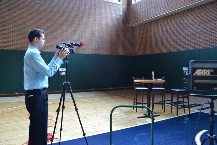 A web team staffer sets up an interview area with a camera and a table.