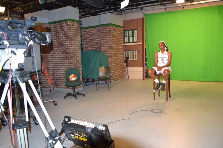 Chelsea Gardner (#10) smiles for a photo in front of a green screen.
