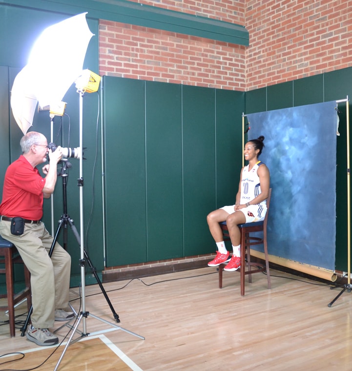 Briann January (#20) sits on a stool in front of a blue background for a photo at Indiana Fever Media Day.
