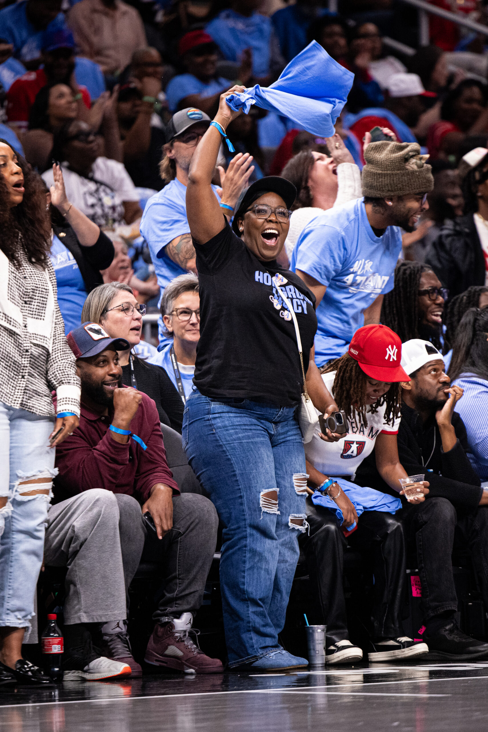Women at Atlanta Dream, WNBA Playoff game swinging a shirt.
