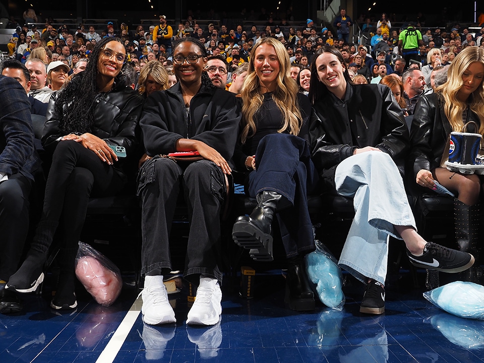 DeWanna Bonner, Aliyah Boston, Lexie Hull and Caitlin Clark sitting courtside at an Indiana Pacers game