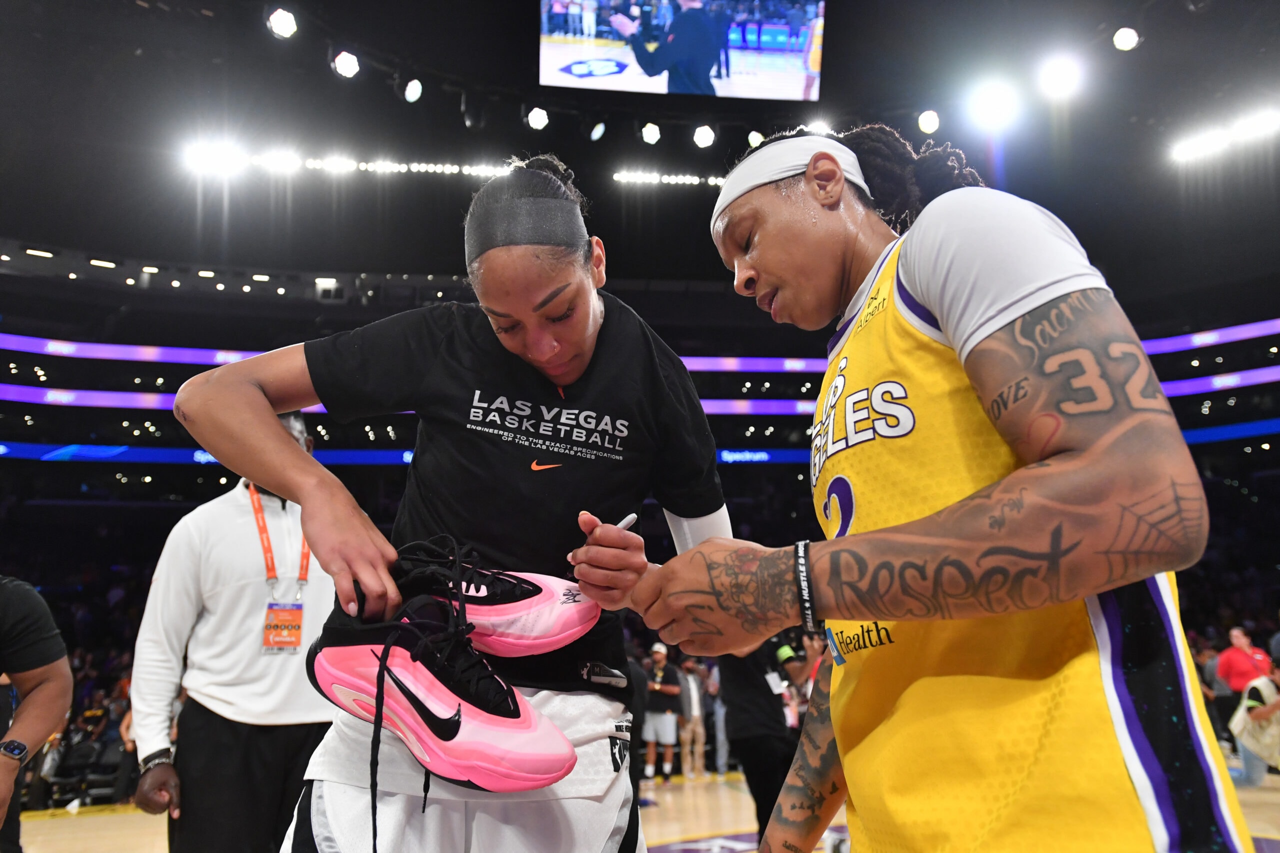 A'ja Wilson #22 of the Las Vegas Aces signs autograph on Emma Cannon #32 of the Los Angeles Sparks shoes after the game on September 11, 2025 at Crypto.Com Arena in Los Angeles, California.